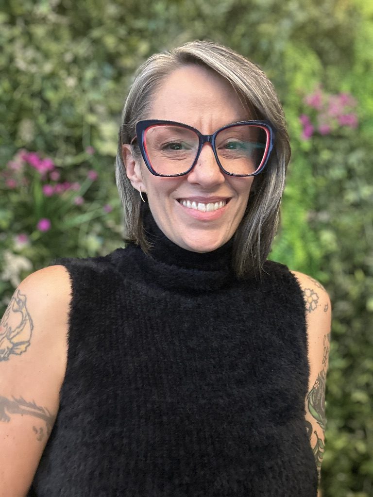 Headshot of Camille Zenobia in red-rimmed glasses and a black turtleneck